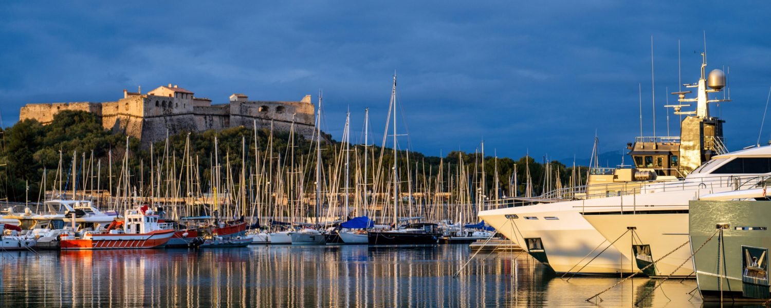 Antibes castle and port with boats and tower over blue sky