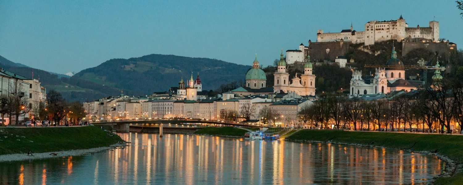 Dusk view down the river with reflections of street lights and a castle in the background